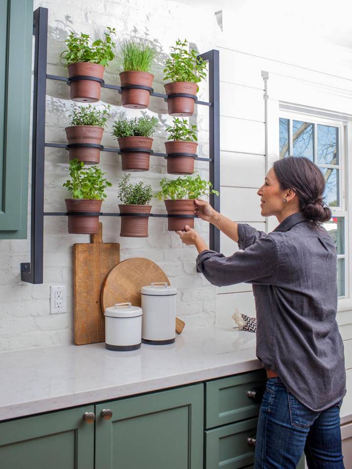 joanna gaines placing potted herbs on wall mounted kitchen rack