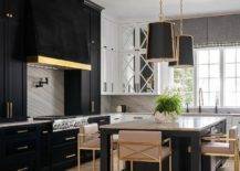 Gold and black hanging shade lights illuminate a marble island top accenting a black kitchen island seating gold and blush pink stools.