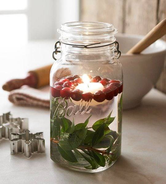 mason jar filled with floating candle water cranberries and greenery
