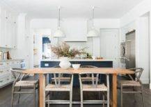 Eat-in kitchen boasting an acorn stained wooden dining table with a set of gray wishbone chairs in an open concept kitchen/dining room space.