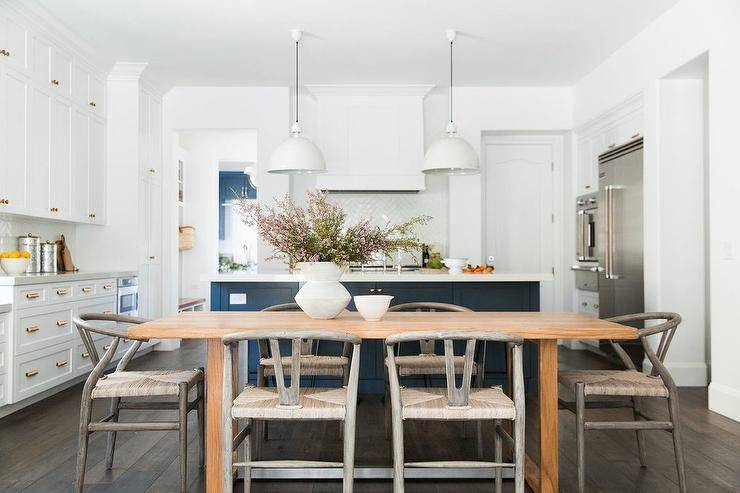 Eat-in kitchen boasting an acorn stained wooden dining table with a set of gray wishbone chairs in an open concept kitchen/dining room space.