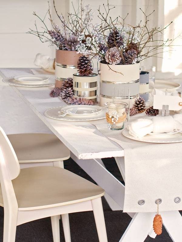 painted paint cans with pinecones and sticks on white Christmas tablescape