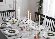 a neutral and simple winter tablescape with mini greenery wreaths for decor, candles in vases with greenery and mini tealights