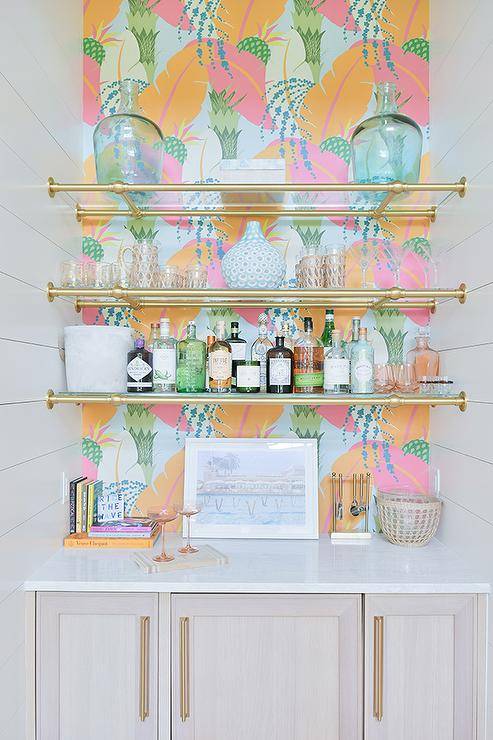 Living room bar nook with blue, orange and pink wallpaper features glass and brass pipe plumbing shelves.
