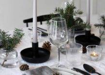 a Scandinavian winter tablescape with pinecones, evergreens, thin and tall candles and black candleholders