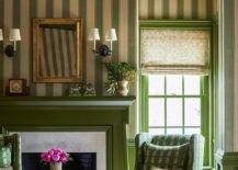 This gorgeous green formal living space features A green fireplace mantel framing a marble surround and fixed against a wall clad in green vertical stripe wallpaper. A gold French mirror hangs above the fireplace and between oil rubbed bronze 2-light sconces. A brass directoire accent table is flanked by green wingback chairs.