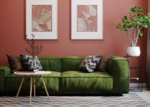 green couch in front of burgundy wall with wall art table and greenery