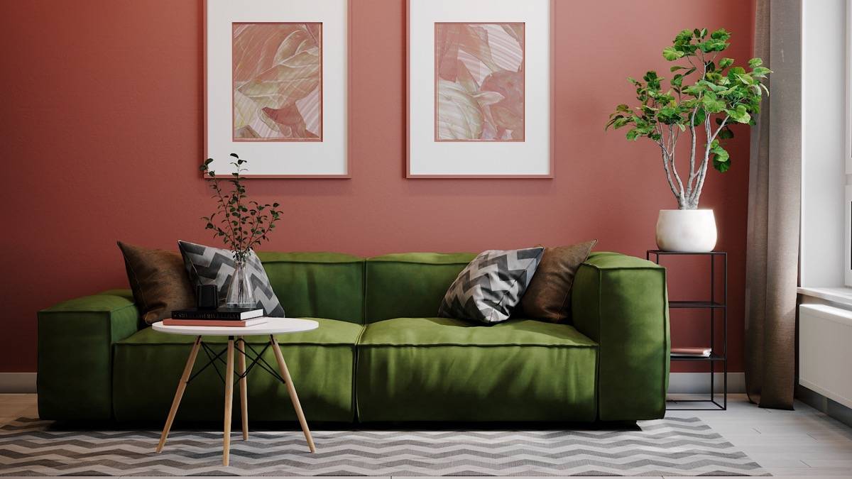 green couch in front of burgundy wall with wall art table and greenery