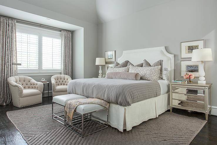 Gray bedroom with white cream legless chair, mirrored nightstand bench and large area rug