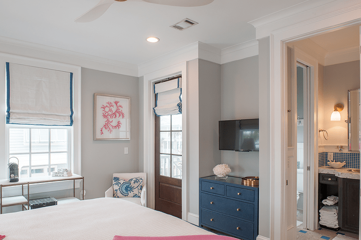 Lovely bedroom nook is fitted with a television mounted over a blue dresser.