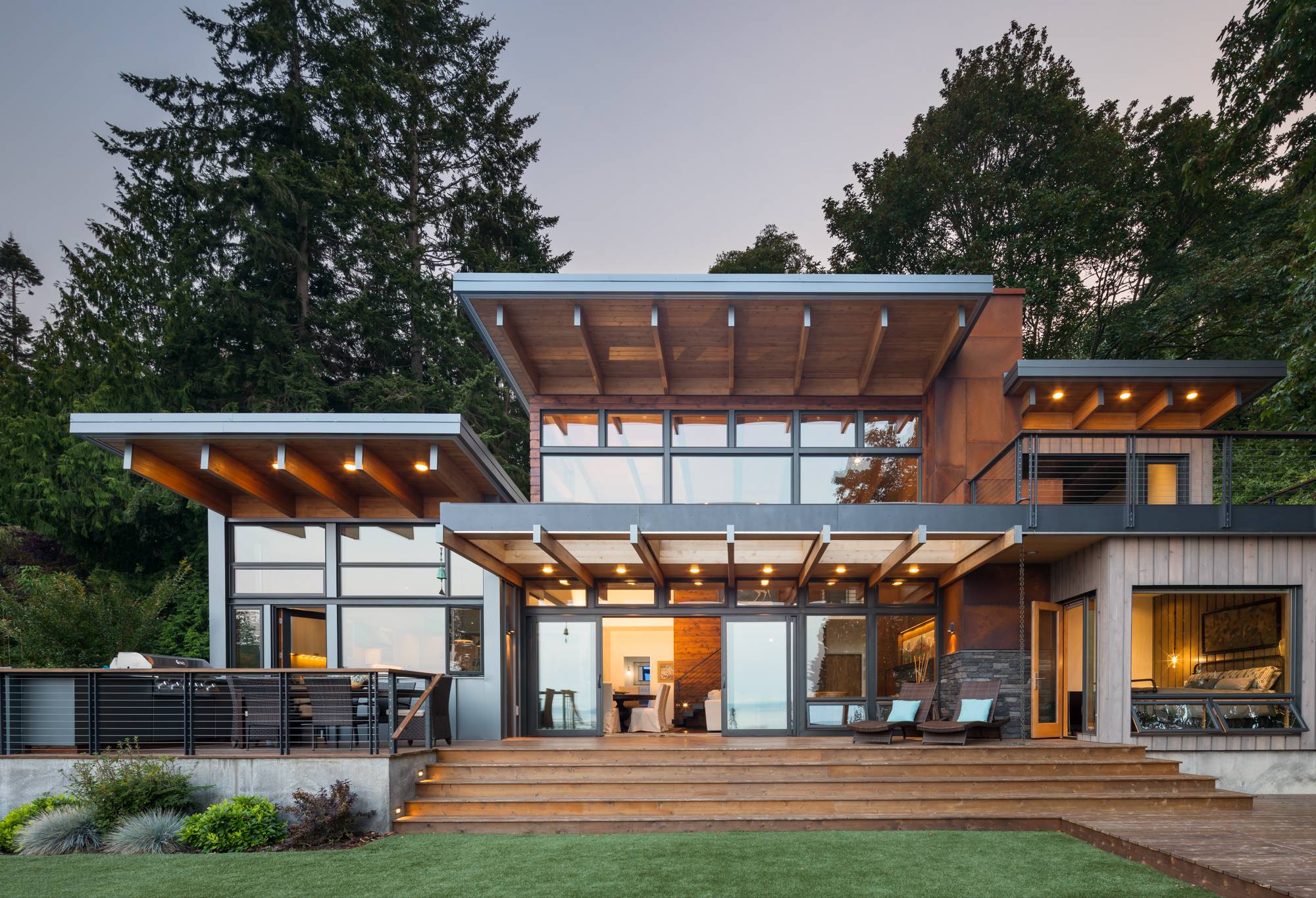 metal and wood framed cabin home with large windows and large wooden deck