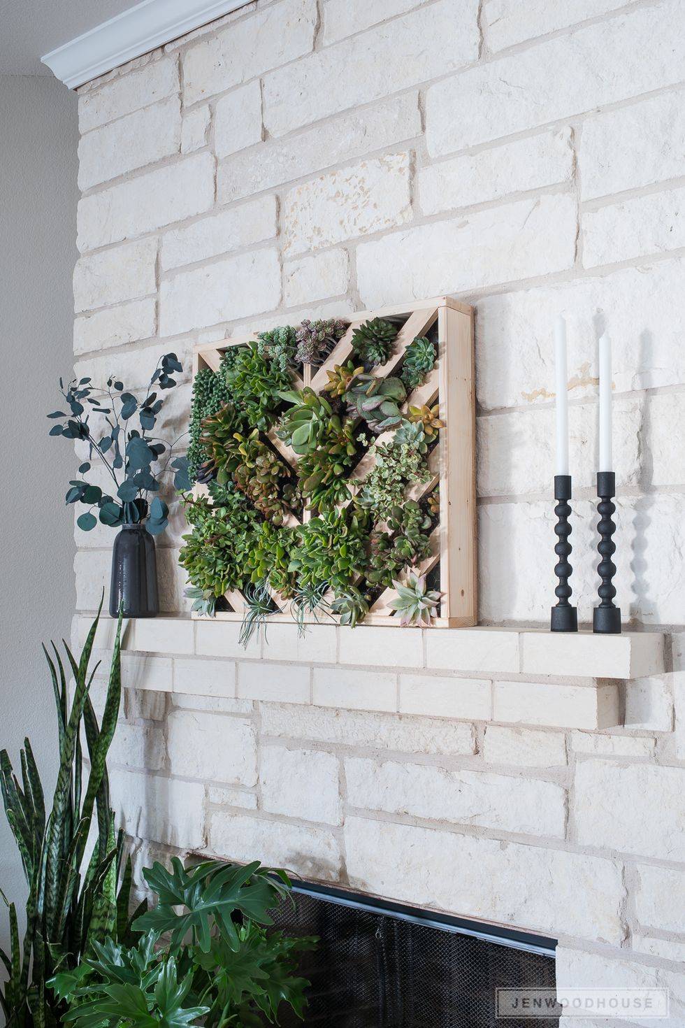 succulent frame box on white brick fireplace mantle with candles and plants
