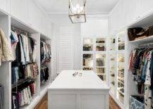 Spacious custom walk in closet features lighted purse cabinets and a white island.