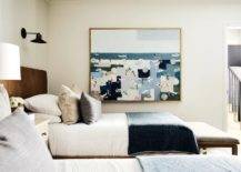 A large beach painting hangs in a welcoming shared cottage bedroom.