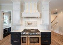 White and gold French range hood designed at a cooktop designed with mosaic accent tiles, an antique swivel arm pot filler and a thermador dual range.