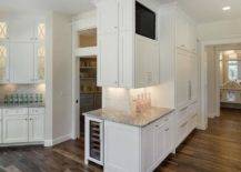 Angled kitchen features white shaker cabinets painted Benjamin Moore Simply White paired with Super White Granite countertops and a mini brick tile backsplash.