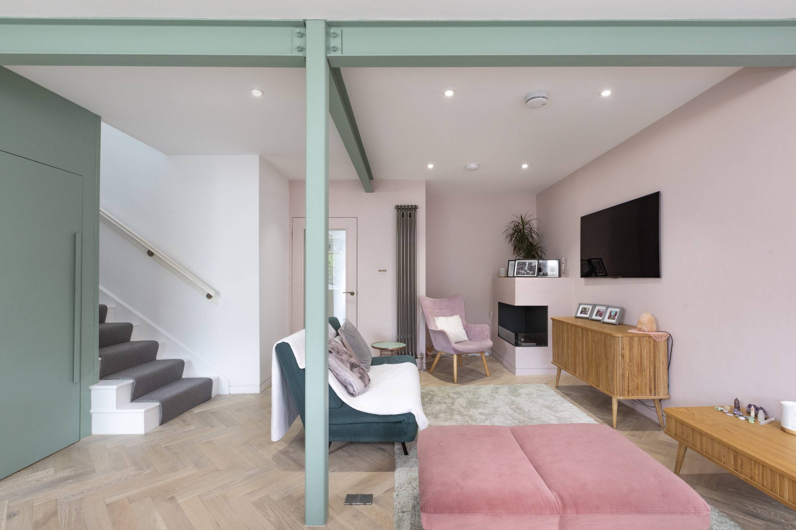 midcentury living room with pink and green accents, exposed industrial beams on ceiling