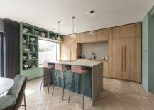 midcentury kitchen with pink barstools at stone island and light wood cabinetry