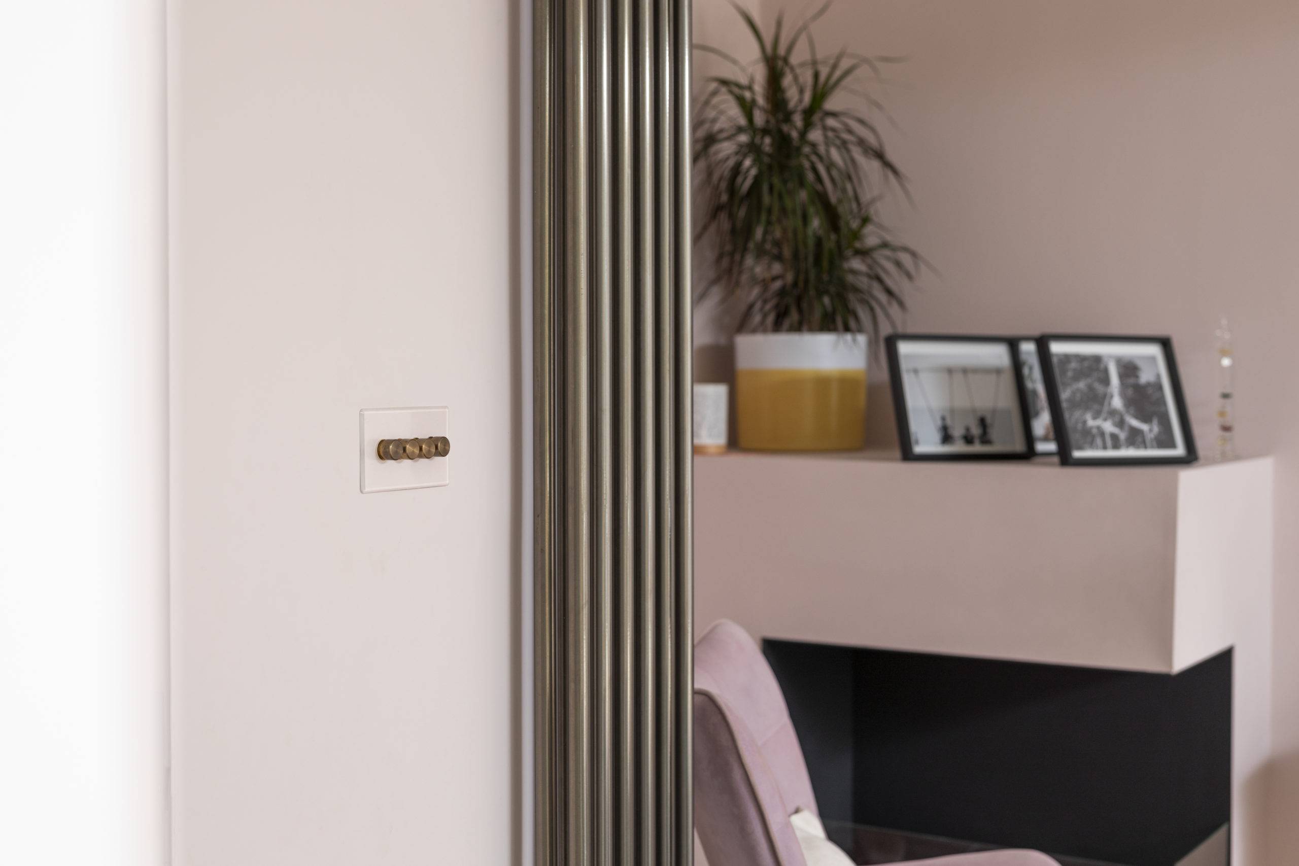 close up of minimal furnishings including fireplace knobs on pink walls