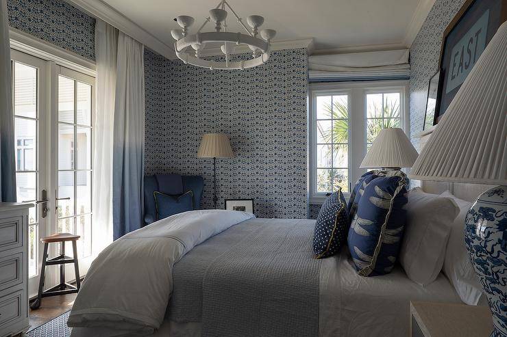Bedroom features a wooden headboard with picture shelf, blue wallpaper and a white chandelier.