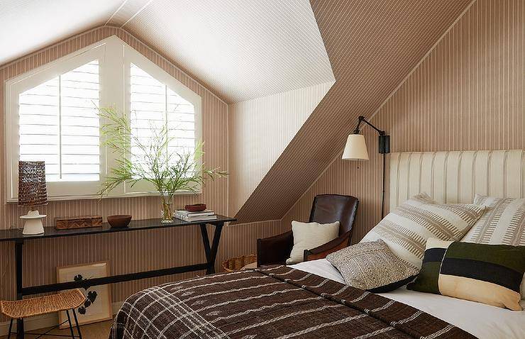 Bedroom features a cream and brown striped headboard on a brown vertical striped rug and brown striped wallpaper,