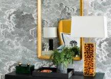 Fornasetti Nuvole Wallpaper complements a black dresser styled with a black tray and a tiger lamp and placed beneath a curved brass mirror.