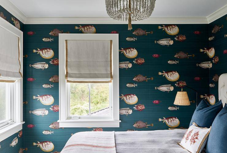 Mr. Blowfish Wallpaper accents a restful bedroom boasting white roman shades with brown trim and a white beaded chandelier.
