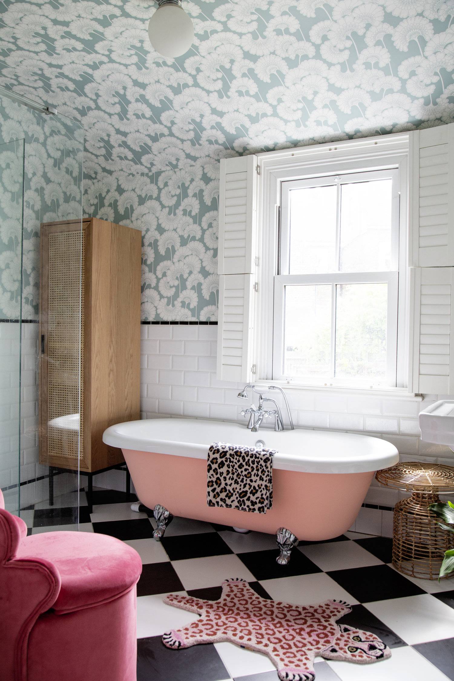 bathroom with turquoise and white wave wallpaper, pink bathtub, leopard print accents, white wooden window shutters