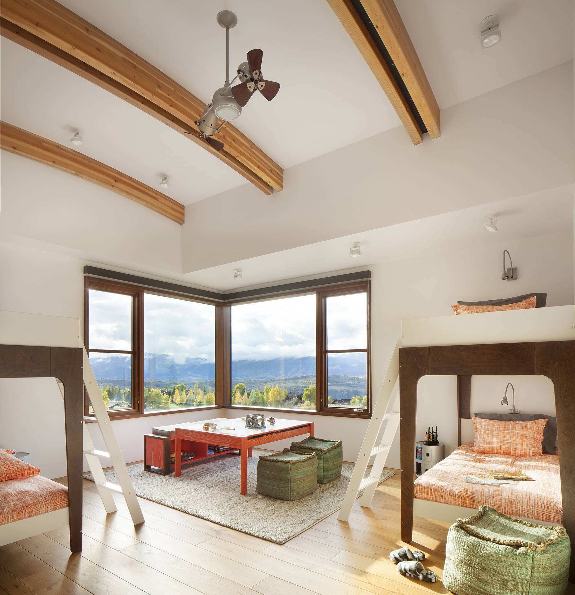 wooden beams on ceiling of large bedroom with bay windows and multiple sets of bunkbeds