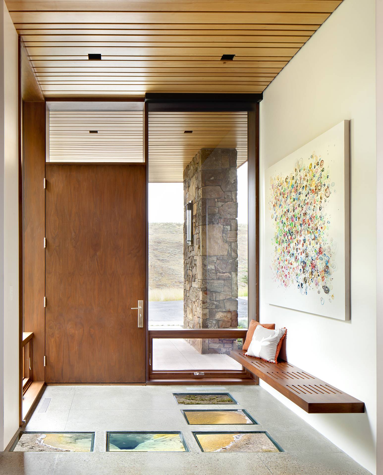 wooden front door in foyer with large windows and glass accents on floor