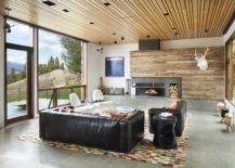 concrete floor living room with black leather couches and wood panelled ceiling