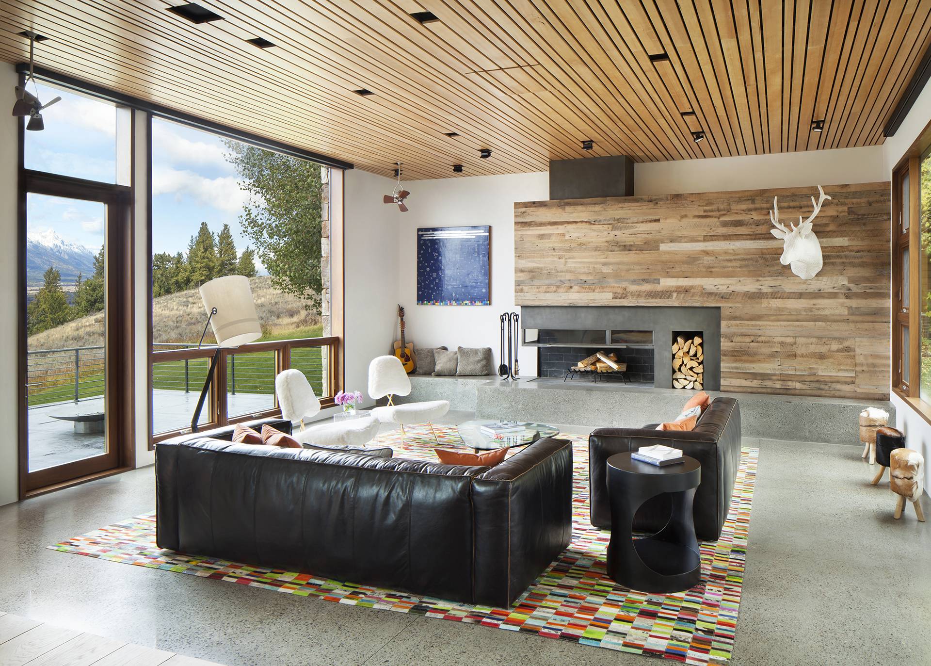concrete floor living room with black leather couches and wood panelled ceiling