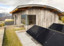 black solar panels on roof of wood panelled home exterior