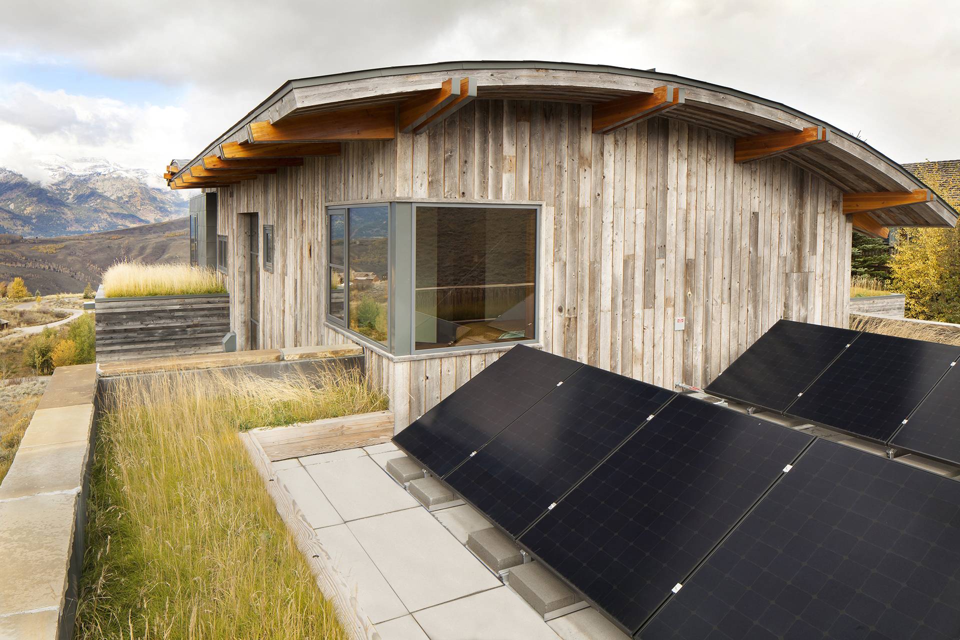 black solar panels on roof of wood panelled home exterior