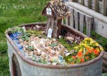 metal trough fairy garden with stones and tree house