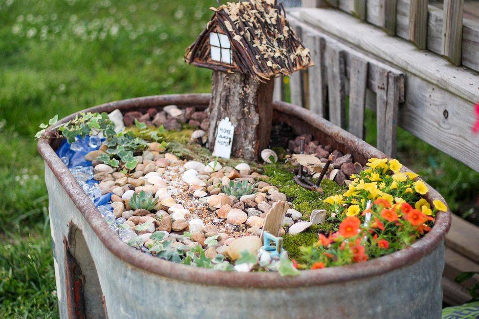 metal trough fairy garden with stones and tree house