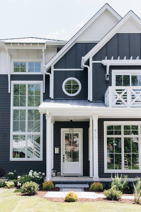White and dark navy blue house boasting white trim and farmstyle appeal with an x trim balcony accented with various siding.