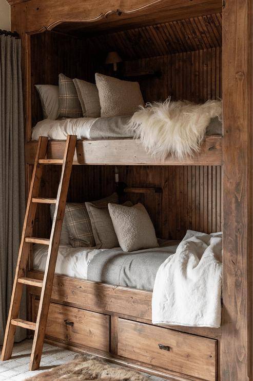 Country bedroom features cabin style wooden bunk beds with gray flannel bedding and a white faux fur throw.