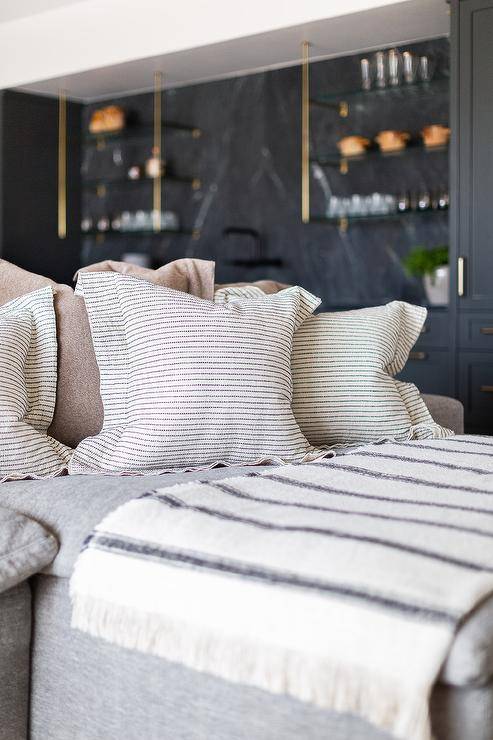 Black stripe pillows and a black striped throw blanket sits on a gray sectional.