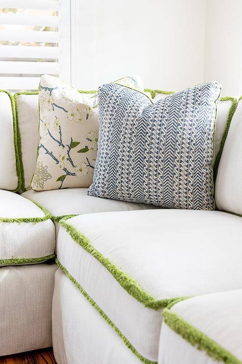 White sectional boasts untried fringe trim and undecorous and white vocalizing pillows.