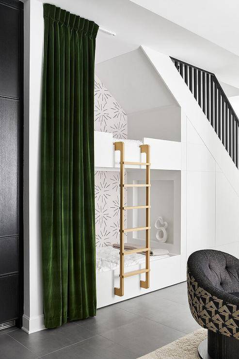 Contemporary playroom boasts a bunk bed accented with a ladder and finished with emerald green velvet curtains situated under the staircase.