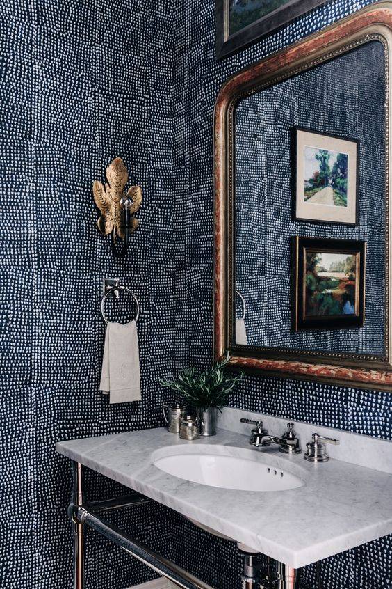 navy and white spotted wallpaper in bathroom with gold accents, white marble vanity counter