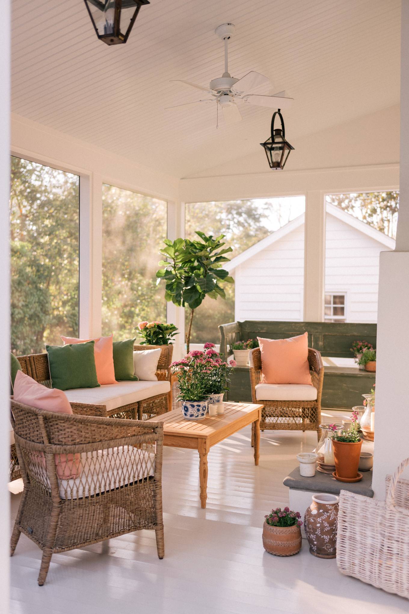 outdoor porch with woven furniture, pinka nd green pillows and floral accents