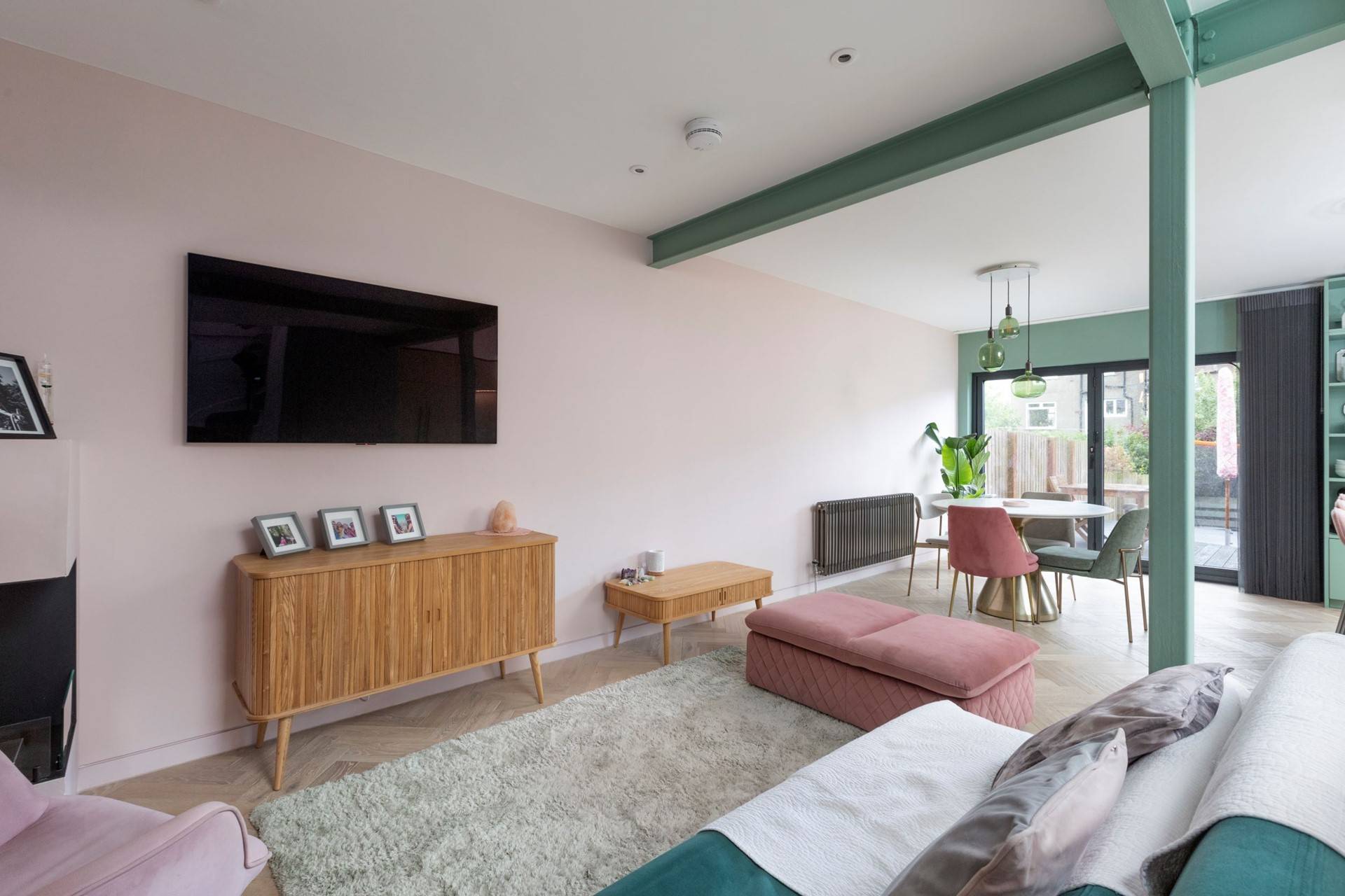 midcentury style living room with light pink walks, green industrial steel beams and grey carpet