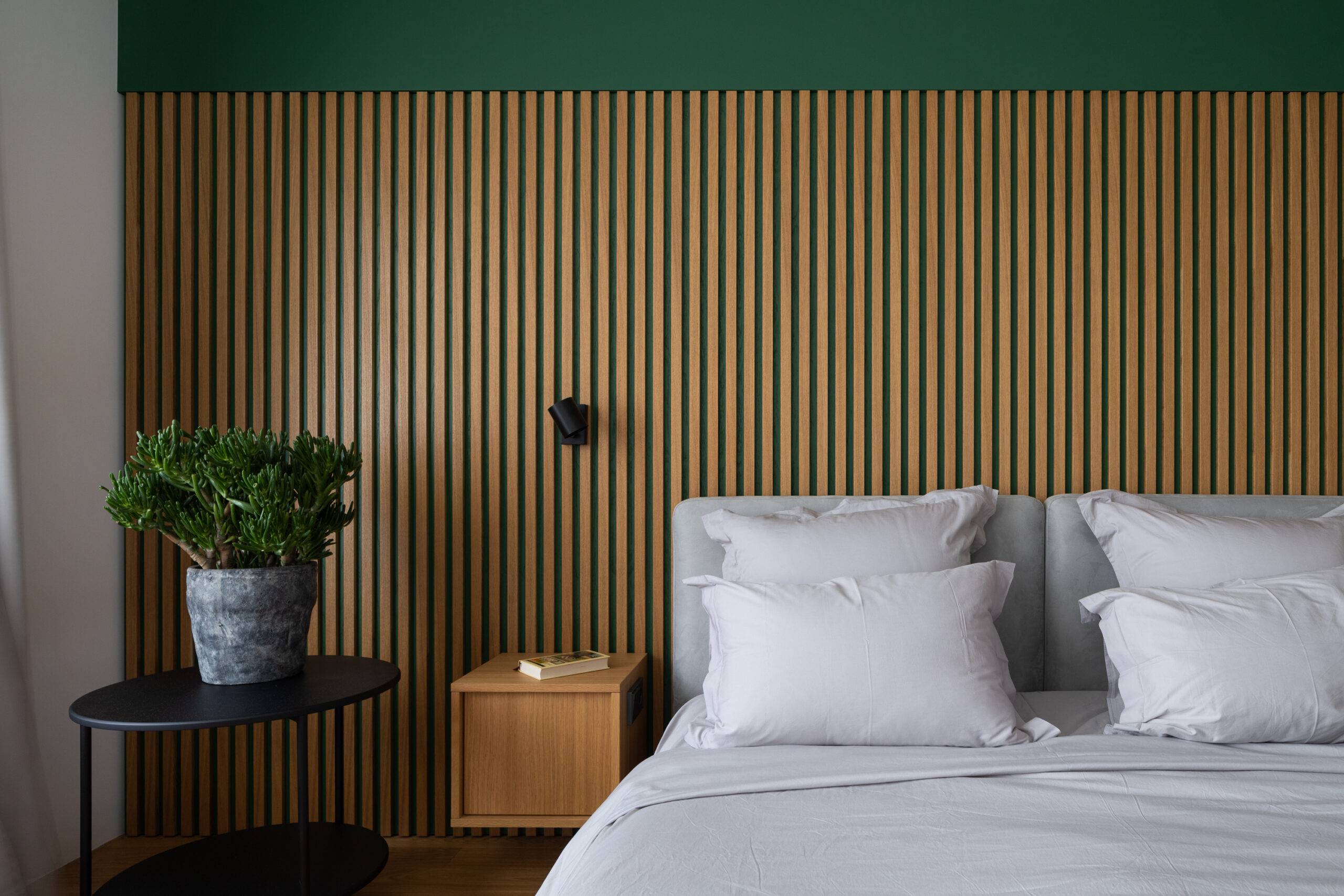 white bedding on bed against wood accent wall with night table