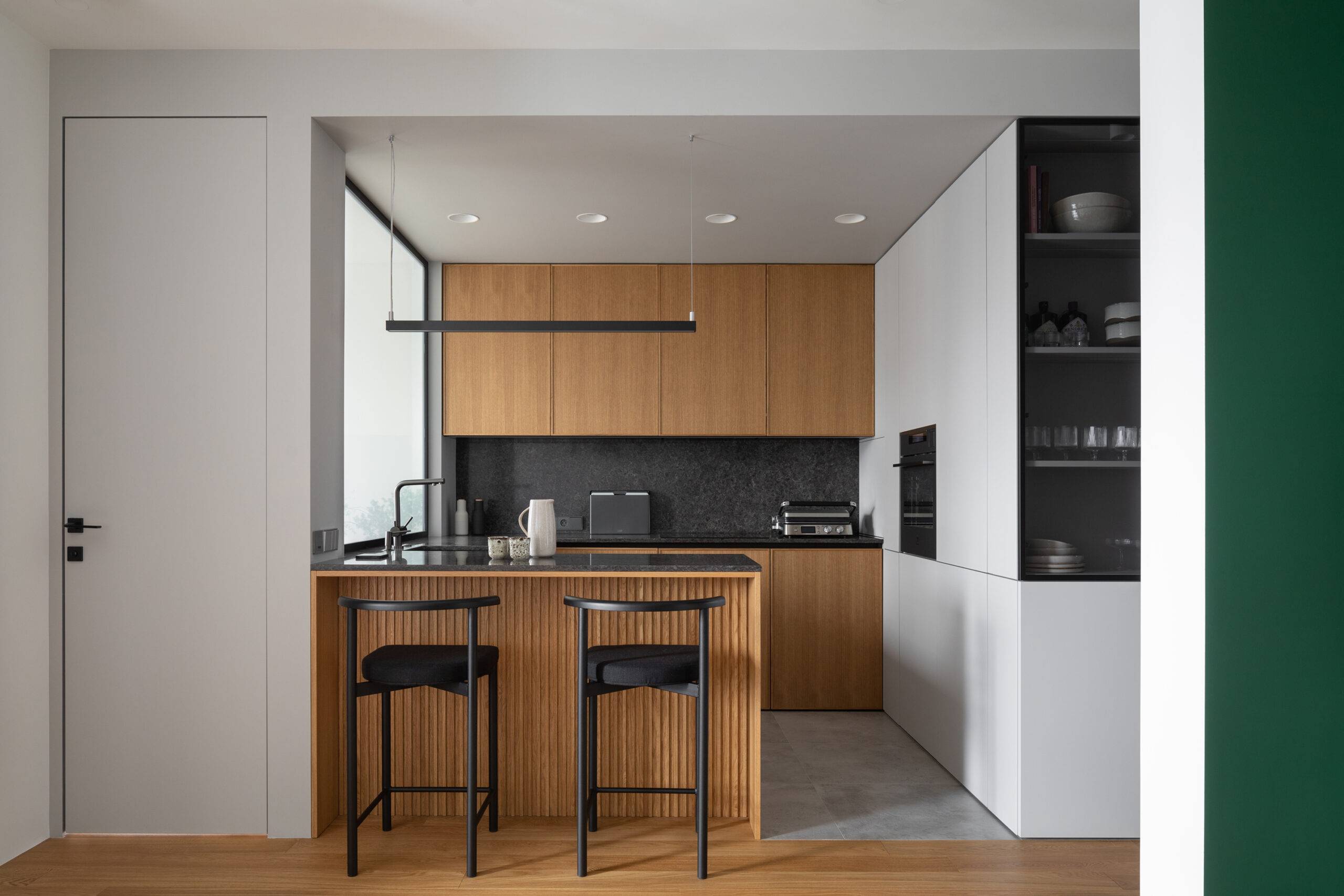 small kitchen with large exterior window over sink, dark wood cupboards and island, black countertops