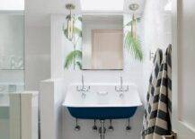 Kids cottage style bathroom features a navy blue trough sink with dual vintage faucets on large white subway tiles and a skylight.