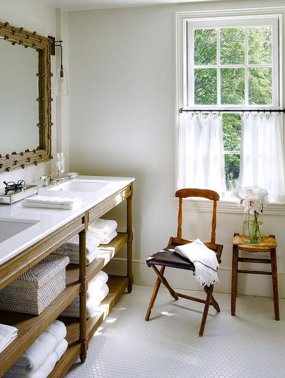 Chic coastal bathroom features a Restoration Hardware Weathered Oak Double Washstand in Brown oak topped with Caesarstone Pure White Quartz under a woven mirror alongside a white hex tiled floor.
