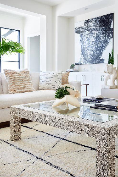 A faux python table sits on a gorgeous Moroccan rug in front of a white sofa accented with beige pillows.