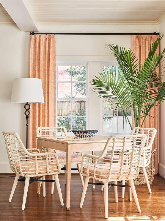 White rattan chairs sit at a square wooden game table illuminated by a black floor lamp.
